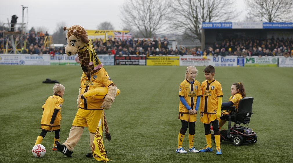 The Sutton mascot, Jenny the Giraffe, entertains the mascots and supporters. AFC Wimbledon